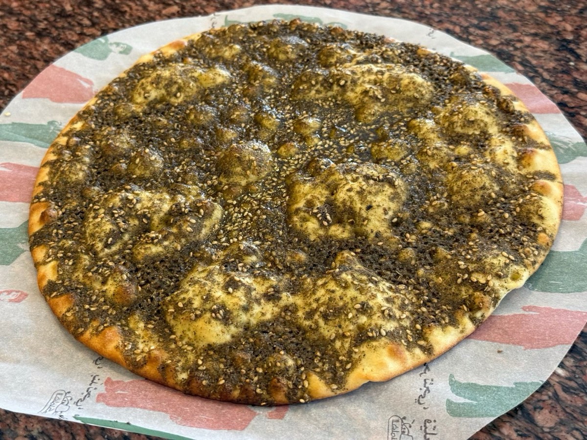 A zaatar manakish, golden at the edges, on patterned paper