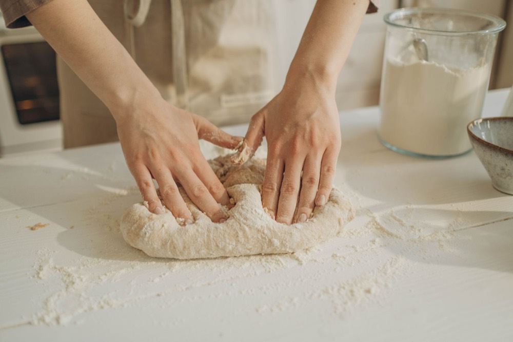 Hands kneading dough on a floured table