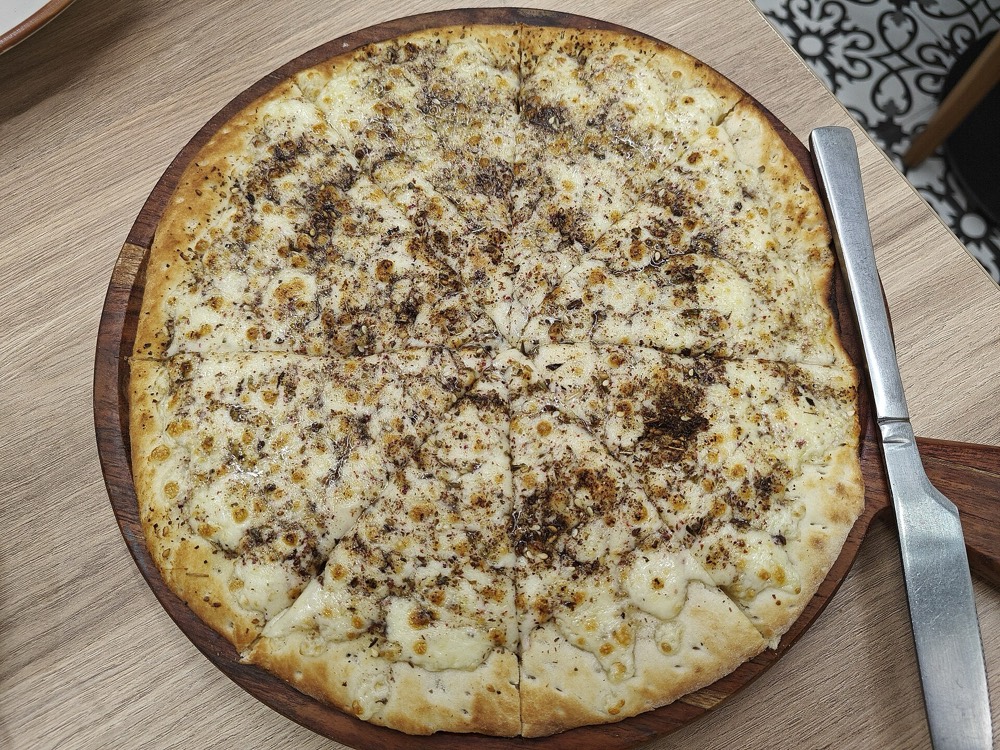 A large zaatar and cheese manakish cut into slices